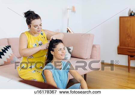 Stock Photo - Friends doing up hair in living room. Fotosearch