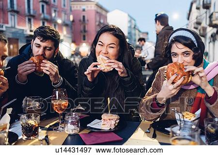 Friends enjoying burger at outdoor cafe, Milan, Italy View Large Photo Image Stock Photo - Friends enjoying burger at outdoor cafe, Milan, Italy. Fotosearch