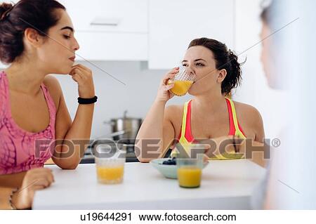Stock Image - Friends enjoying juice at home after exercise. Fotosearch