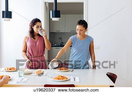 Stock Photo - Friends enjoying lunch at home. Fotosearch