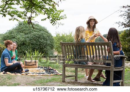 Stock Image - Friends enjoying picnic in countryside. Fotosearch
