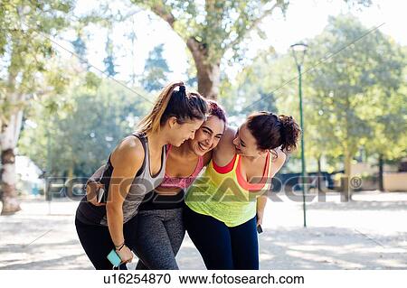 Stock Image - Friends exercising and laughing in park. Fotosearch