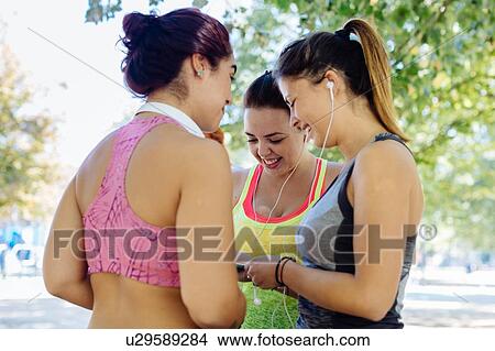 Picture - Friends exercising and using cellphone in park. Fotosearch