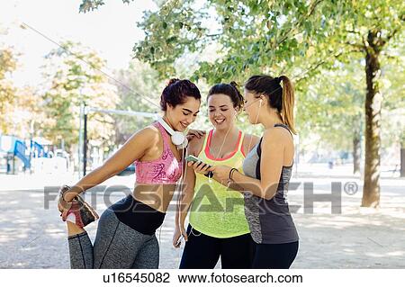 Friends exercising and using cellphone in park View Large Photo Image Stock Image - Friends exercising and using cellphone in park. Fotosearch
