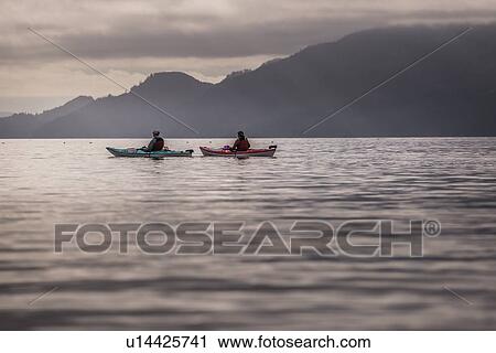 Stock Image - Friends kayaking in lake, Johnstone Strait, Telegraph Cove, Canada. Fotosearch