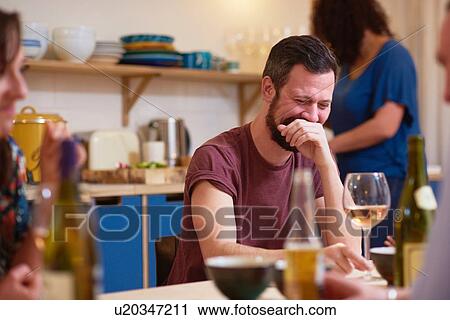 Stock Image - Friends laughing at dinner party. Fotosearch