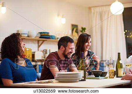 Stock Photo - Friends laughing at dinner party. Fotosearch