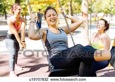 Friends playing at swing in park View Large Photo Image Stock Image - Friends playing at swing in park. Fotosearch