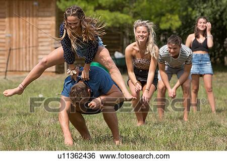 Stock Photograph - Friends playing leapfrog in park. Fotosearch