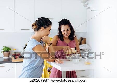 Stock Photo - Friends preparing lunch in kitchen. Fotosearch