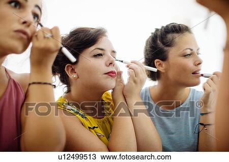 Friends putting on makeup at mirror View Large Photo Image Stock Image - Friends putting on makeup at mirror. Fotosearch