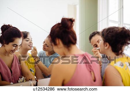 Stock Photograph - Friends putting on makeup at mirror. Fotosearch