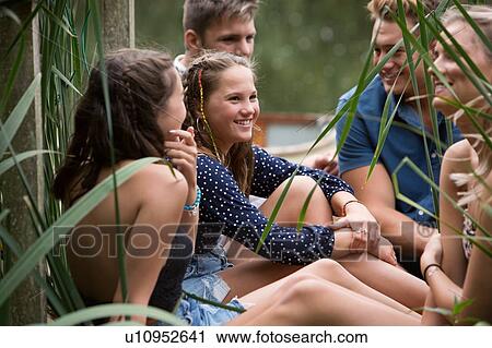 Stock Image - Friends relaxing by lake. Fotosearch