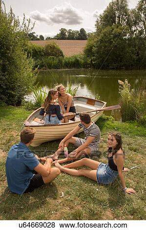 Stock Photo - Friends relaxing by lake. Fotosearch