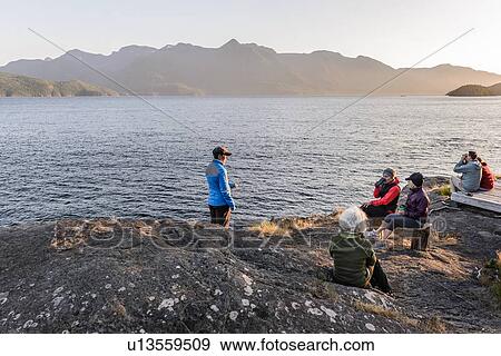 Stock Photo - Friends relaxing by lakeside, Johnstone Strait, Telegraph Cove, Canada. Fotosearch