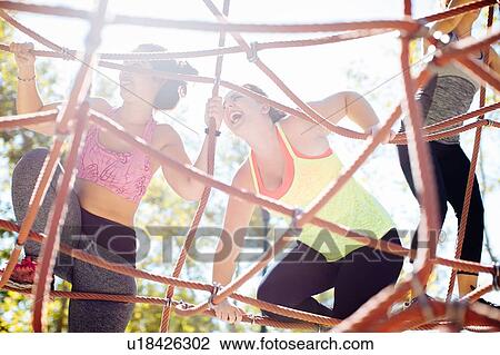 Stock Image - Friends rope climbing in park. Fotosearch