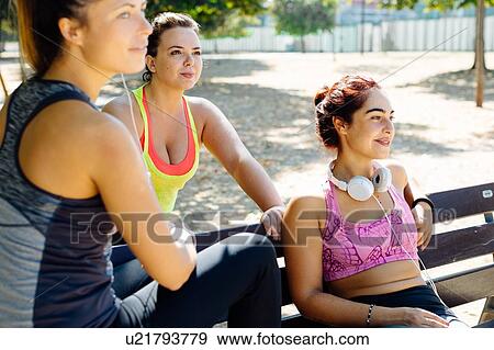 Stock Photo - Friends taking break from exercise in park. Fotosearch