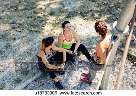 Friends taking break from exercise in park View Large Photo Image Stock Photograph - Friends taking break from exercise in park. Fotosearch