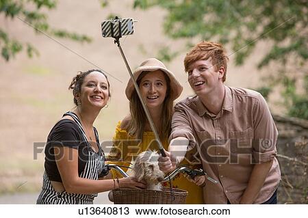 Friends taking selfie with pet dog in countryside View Large Photo Image Stock Image - Friends taking selfie with pet dog in countryside. Fotosearch