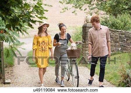 Picture - Friends taking walk with pushbike and pet dog in countryside. Fotosearch