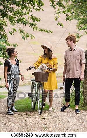 Stock Photo - Friends taking walk with pushbike and pet dog in countryside. Fotosearch