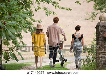 Friends taking walk with pushbike in countryside View Large Photo Image Stock Photography - Friends taking walk with pushbike in countryside. Fotosearch