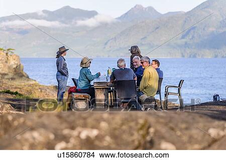 Picture - Friends talking at dinner on lakeside, Johnstone Strait, Telegraph Cove, Canada. Fotosearch