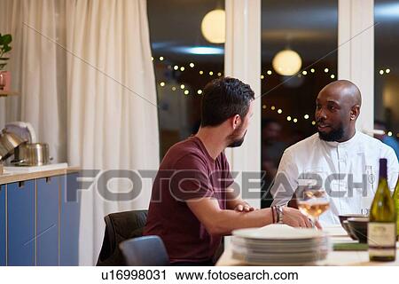 Stock Image - Friends talking at dinner party. Fotosearch