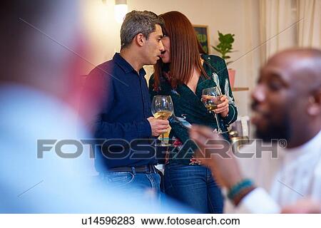 Stock Image - Friends talking, couple whispering at dinner party. Fotosearch