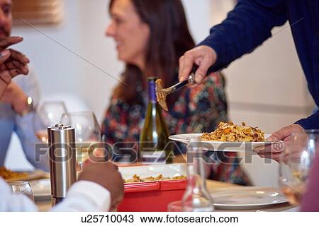 Friends talking, man serving food at dinner party View Large Photo Image Stock Image - Friends talking, man serving food at dinner party. Fotosearch
