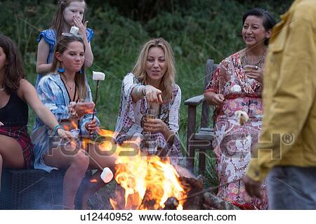 Friends toasting marshmallows at bonfire party in park View Large Photo Image Stock Image - Friends toasting marshmallows at bonfire party in park. Fotosearch