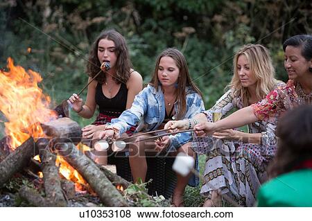 Friends toasting marshmallows at bonfire party in park View Large Photo Image Stock Photo - Friends toasting marshmallows at bonfire party in park. Fotosearch