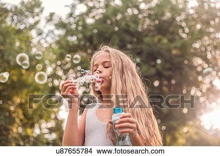 Picture - Girl blowing bubbles in park. Fotosearch