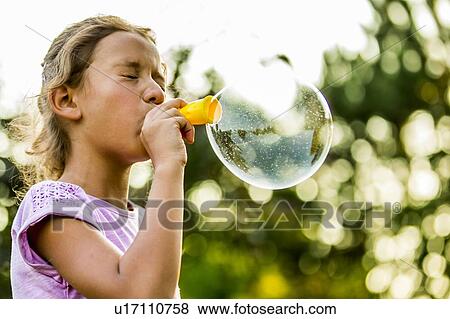 Girl blowing bubbles with bubble wand in park. View Large Photo Image Stock Photo - Girl blowing bubbles with bubble wand in park.. Fotosearch