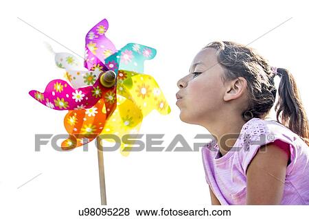 Stock Photo - Girl blowing multi coloured paper windmill, close-up.. Fotosearch