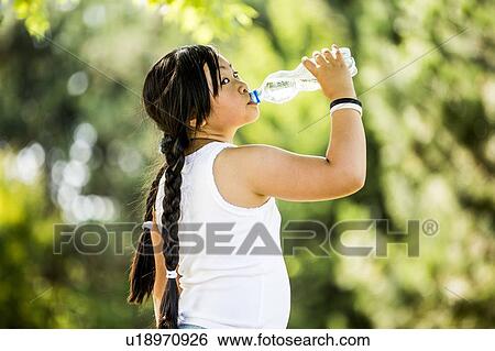 Girl drinking water from plastic bottle in park, portrait. View Large Photo Image Stock Photograph - Girl drinking water from plastic bottle in park, portrait.. Fotosearch