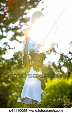 Stock Photography - Girl holding bunch of balloons in park.. Fotosearch
