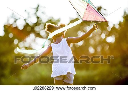 Girl holding kite and running in park. View Large Photo Image Stock Photo - Girl holding kite and running in park.. Fotosearch