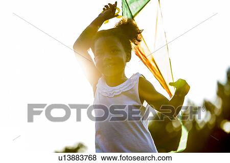 Girl holding kite in park, smiling. View Large Photo Image Stock Photo - Girl holding kite in park, smiling.. Fotosearch