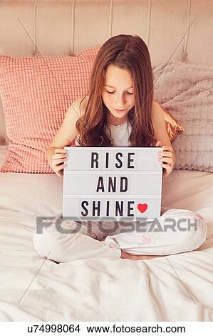 Picture - Girl holding up sign in bed. Fotosearch