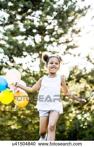 Girl in bunches running with balloons in park, smiling. View Large Photo Image Stock Image - Girl in bunches running with balloons in park, smiling.. Fotosearch