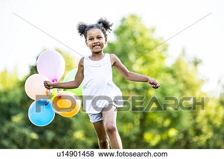 Girl in bunches running with balloons in park, smiling. View Large Photo Image Stock Photo - Girl in bunches running with balloons in park, smiling.. Fotosearch