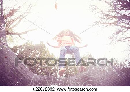 Girl jumping on trampoline, low angle view View Large Photo Image Stock Image - Girl jumping on trampoline, low angle view. Fotosearch