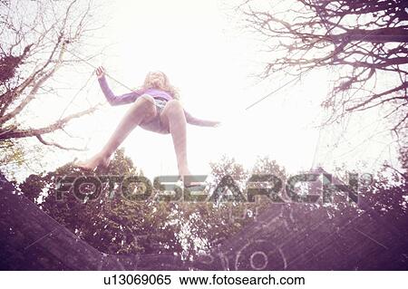 Girl jumping on trampoline, low angle view View Large Photo Image Stock Photography - Girl jumping on trampoline, low angle view. Fotosearch