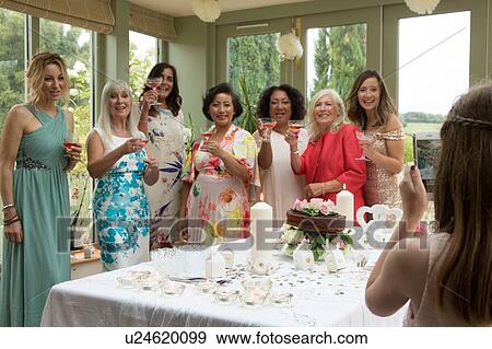 Stock Photo - Girl photographing female wedding guests at reception. Fotosearch