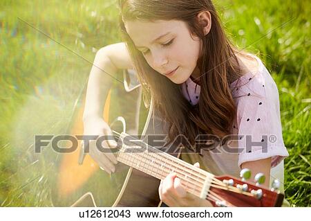 Girl playing guitar on grass View Large Photo Image Stock Image - Girl playing guitar on grass. Fotosearch