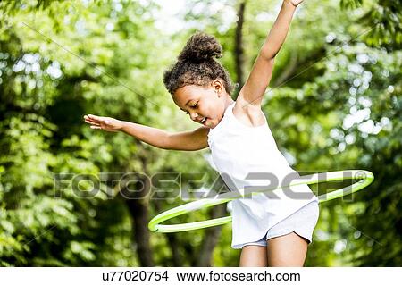 Girl playing with hula hoop in park, smiling. View Large Photo Image Picture - Girl playing with hula hoop in park, smiling.. Fotosearch