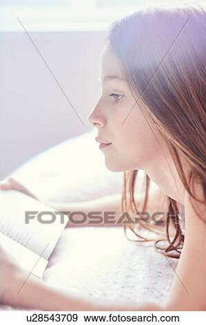 Stock Photo - Girl reading book and day dreaming. Fotosearch