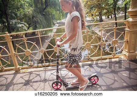 Girl riding on scooter in park View Large Photo Image Stock Photography - Girl riding on scooter in park. Fotosearch