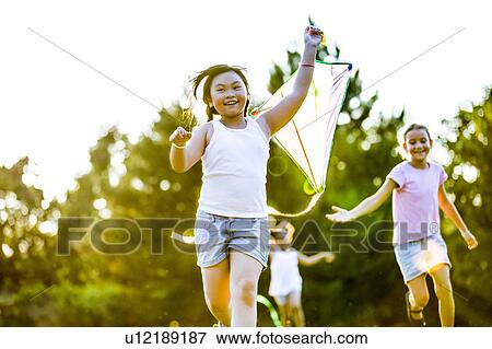 Girl running with Kite and two girls running behind her in park. View Large Photo Image Stock Photo - Girl running with Kite and two girls running behind her in park.. Fotosearch